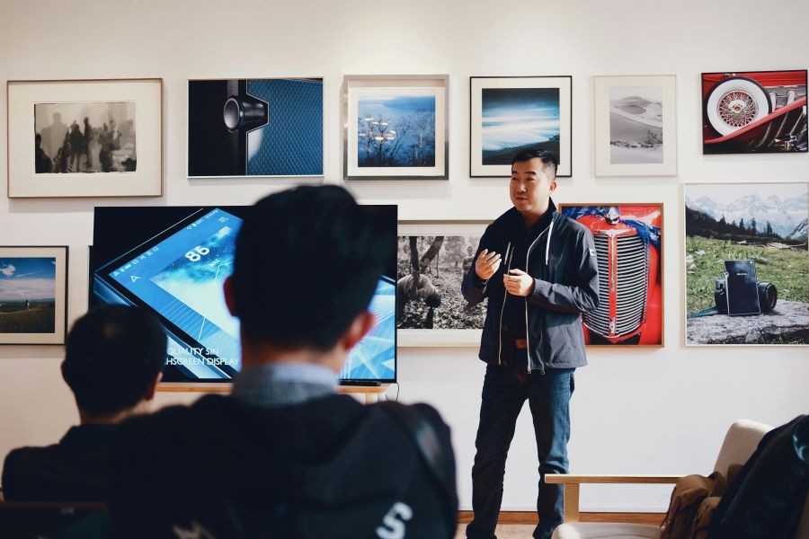 A man next to a display with photos in the background.