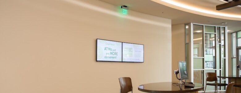 two digital signage screens mounted on a wall in a bank
